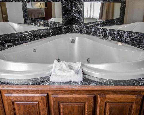斯普林代尔Sleep Inn & Suites Springdale West的浴室设有白色浴缸及镜子