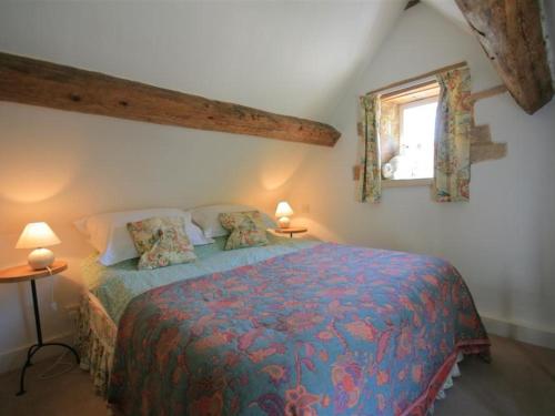QueningtonMayfly Cottage的一间卧室配有一张带蓝色棉被的床和窗户。