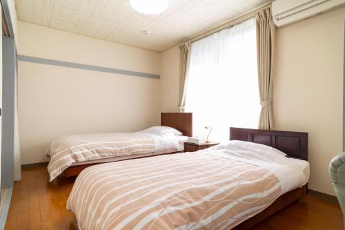 藤泽Enoshima Apartment Hotel的卧室设有两张床,带窗户