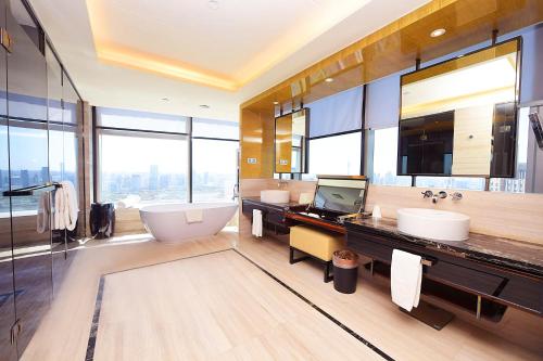 天津唐拉雅秀天津酒店的一间带两个盥洗盆和浴缸的浴室以及大窗户。