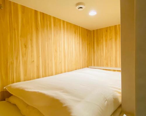 大阪bnb+ Shinsaibashi的木墙客房的一张床位