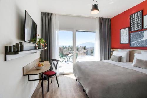 日内瓦Appart'City Collection Genève Aéroport - Vernier的配有一张床、一张书桌和一扇窗户的酒店客房