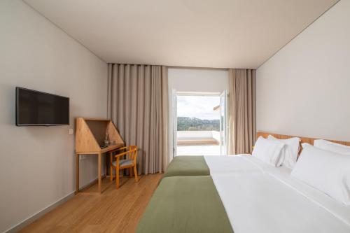 维塞乌Montebelo Principe Perfeito Viseu Garden Hotel的酒店客房配有一张床、一张书桌和一台电视。
