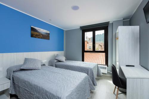纳赫拉Apartamentos Turísticos San Lorenzo的一间卧室设有两张床、一张桌子和一个窗口。