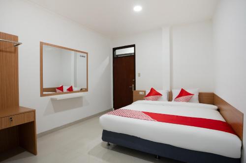 万隆Super OYO 3209 Hegarbudhi Residence的一间卧室配有一张带红色枕头的大床