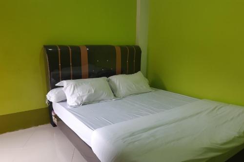 LubukpakamOYO 3487 Es Em Je Residence的绿色卧室配有带白色床单和枕头的床