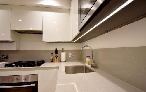 伦敦Northside Apartments Ealing的厨房配有白色橱柜和水槽
