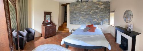 Saint-Georges-de-LuzençonLes Tilleuls的一间卧室设有一张床和石墙