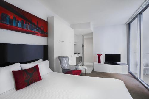 布里斯班曼特拉城区公寓式酒店的卧室配有白色的床和红色枕头