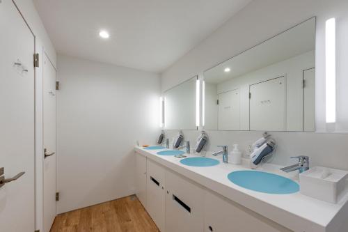东京plat hostel keikyu haneda home的一间带三个水槽和大镜子的浴室