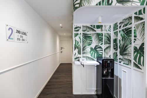 新加坡Philip Hotel的走廊上设有白色墙壁,墙上贴着棕榈叶壁纸