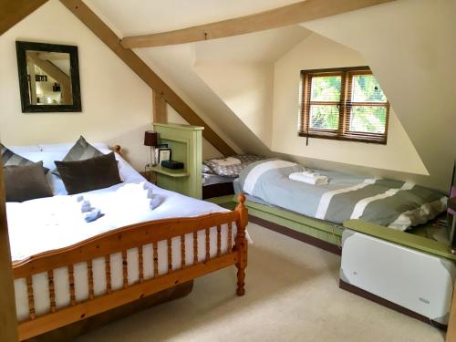 斯通豪斯Greencourt Loft - The Cotswold Way, Stroud的阁楼卧室设有两张床和窗户。