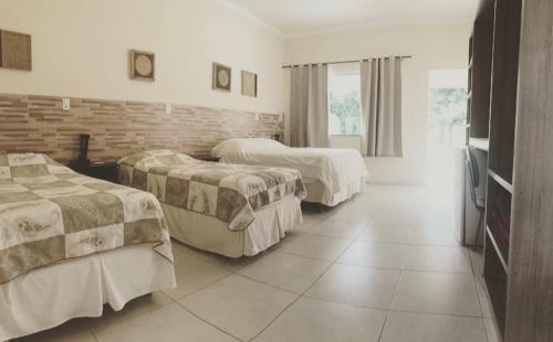 克拉鲁河畔卡尔穆Pousada Pontal do Lago的酒店客房带两张床和砖墙