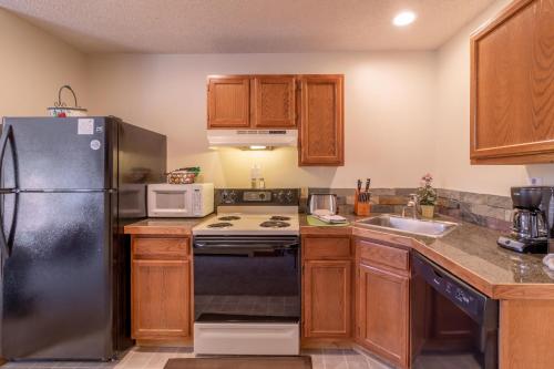 埃斯蒂斯帕克Woodlands on Fall River的厨房配有木制橱柜和黑色冰箱。