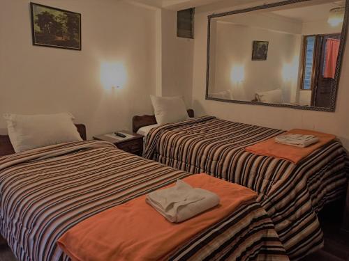 库斯科Hostal Tu Hogar的酒店客房,设有两张床和镜子