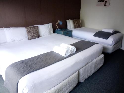 凯里凯里伍德兰兹汽车旅馆的酒店客房内的三张床,配有白色床单
