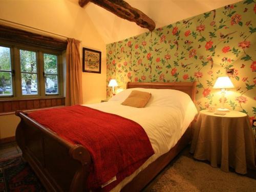 伯福德Tannery Cottage的一间卧室配有一张带花卉壁纸的大床