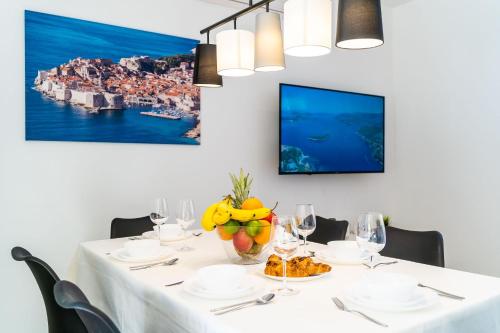 杜布罗夫尼克Apartment 'Holiday Above Dubrovnik'的餐桌,配有白色的桌布和水果花瓶