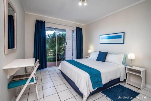 乌姆德洛蒂Tahiti 10的一间卧室配有一张床、一张书桌和一个窗户。
