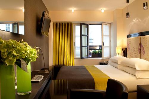 巴黎Hôtel Caron le Marais的酒店客房设有床和窗户。
