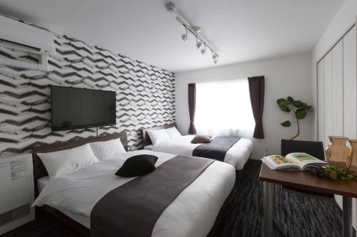 札幌Hotel ONE'S RESIDENCE的酒店客房设有两张床和一台平面电视。