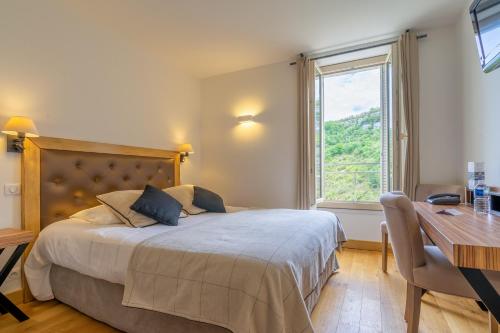 罗卡马杜尔Hotel Beau Site - Rocamadour的一间卧室配有一张床、一张书桌和一个窗户。