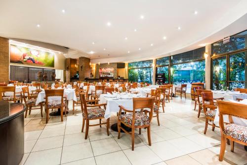马那瓜会议中心假日旅馆的餐厅设有白色的桌椅和窗户。