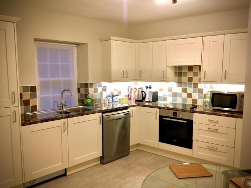 La VillaisePeaceful 2 bedroom granite country dower house的厨房配有白色橱柜和不锈钢用具