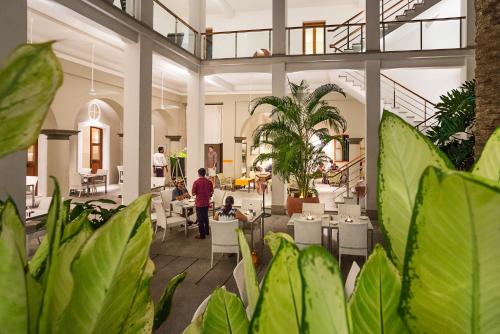 蓬蒂切里Villa Shanti - Heritage Hotel for Foodies的大堂里有人坐在桌子和植物上