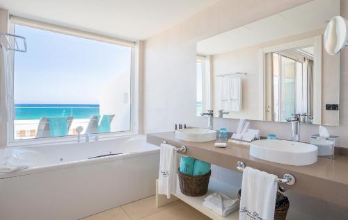 卡门港Hotel Lava Beach的一间带两个盥洗盆、浴缸和窗户的浴室