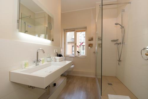 杜塞尔多夫Carlstadt Suites Düsseldorf的白色的浴室设有水槽和淋浴。