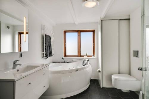 霍尔斯特布罗Marieshus的白色的浴室设有浴缸、水槽和卫生间。
