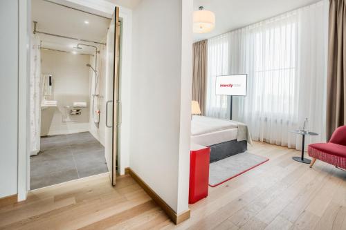 汉堡IntercityHotel Hamburg-Barmbek的一间卧室配有一张床和一张红色椅子