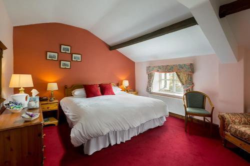 哈罗盖特The Queens Head Kettlesing的一间卧室配有一张大床和红地毯