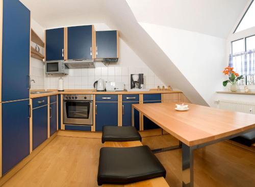 蒂门多夫Appartements Am Reiterhof Seepferdchen的厨房配有蓝色橱柜和木桌
