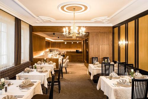 圣克里斯蒂娜Hotel Touring Dolomites的餐厅配有白色的桌椅和吊灯