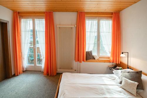 LotzwilHotel Restaurant Bad Gutenburg的一间卧室配有床和带橙色窗帘的窗户。
