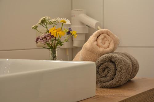 达米尔斯Hotel Garni Alpina的浴室水槽配有毛巾和花瓶