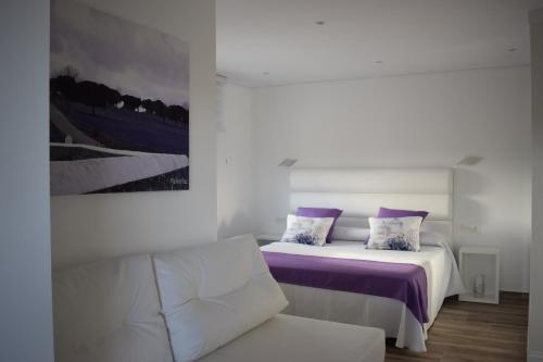 EndrinalHotel Restaurante Racha的一间卧室配有一张带紫色床单的床和一张沙发
