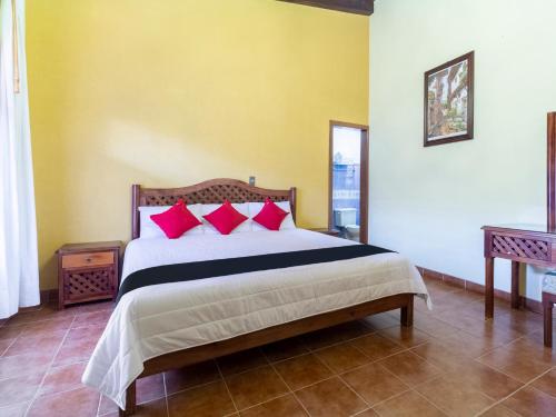 科米坦德多明格斯Hotel Jardín de Tereza的一间卧室配有一张带红色枕头的大床