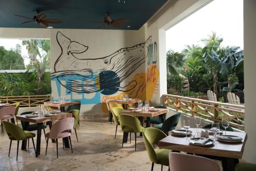 拉斯特拉纳斯Saman Boutique Hotel的一间设有桌椅的餐厅,墙上挂着壁画