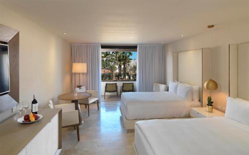 卡波圣卢卡斯Paradisus Los Cabos - Adults Only - All Inclusive的酒店客房设有两张床和一张桌子。