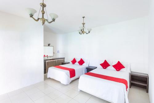 Subteniente LópezOYO Hotel Rio的白色客房的两张床,配有红色枕头