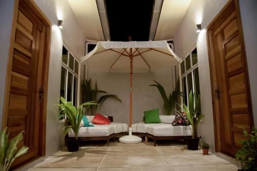 FeridhooEscapism Maldives的一个带两张白色沙发和一把伞的门廊