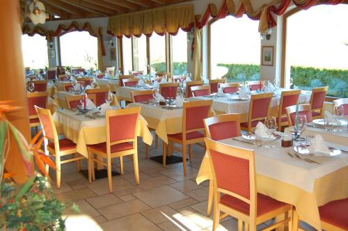 博尔扎诺潘蓝斯塔雷花园酒店的餐厅设有白色的桌椅和窗户。