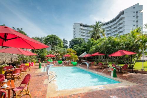 圣玛尔塔加连得可麦仑酒店 - 全包的一个带桌椅和红色遮阳伞的游泳池