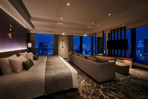 大阪The Royal Park Hotel Iconic Osaka Midosuji的一间卧室配有一张床、一张沙发和一台电视