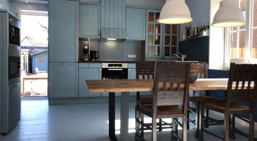 韦斯特兰Haus Noge Sylt - Offizierhaus Design Appartments strandnah的厨房配有蓝色橱柜和木桌及椅子