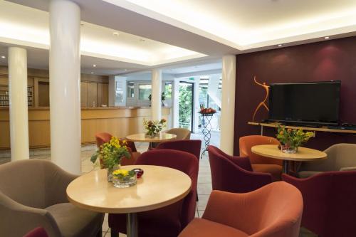 斯图加特凯莱高级酒店的一间设有桌椅和平面电视的等候室