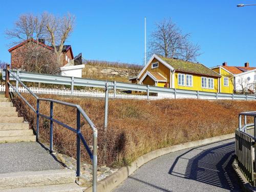 格雷伯斯塔德5 person holiday home in GREBBESTAD的山丘上一座黄色的房子,有栅栏和楼梯